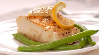 A photograph of pan-roasted paiche with herbs, lemon and green beans.